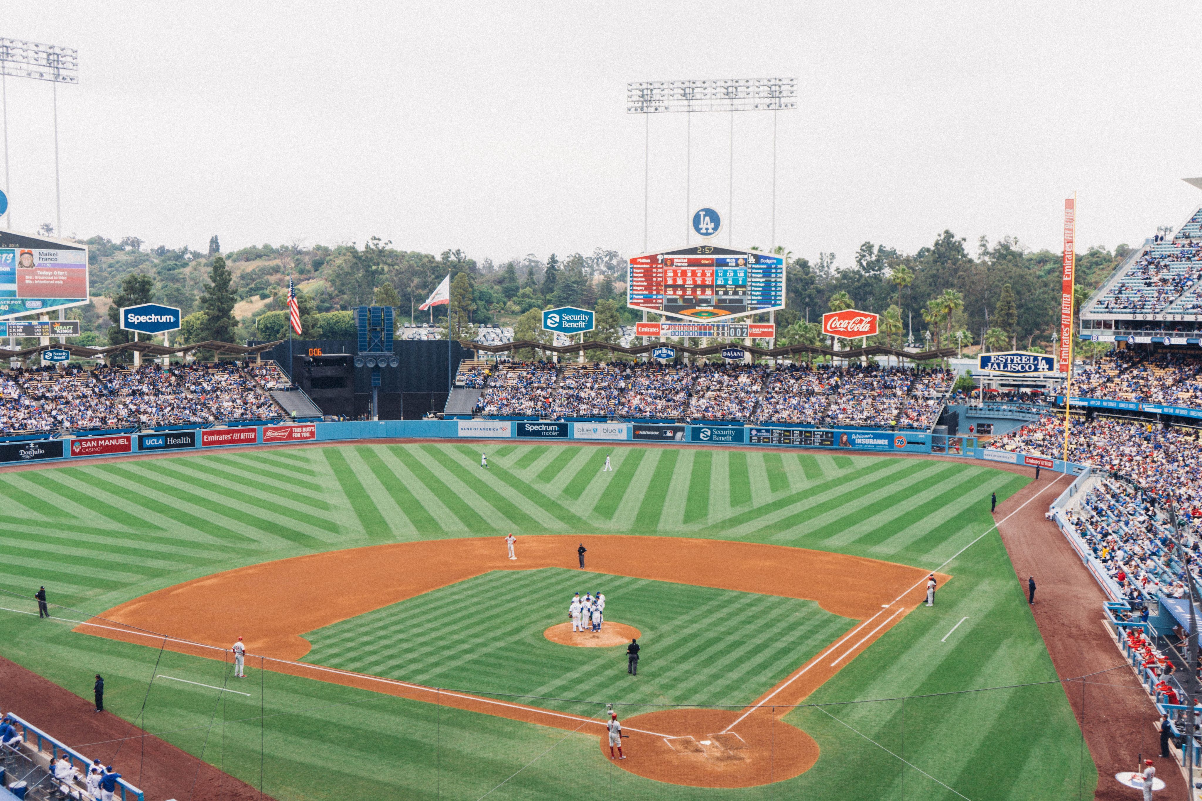 Dodgers Stadium in Los Angeles, CA during an afternoon game. The stands are full of fans while the Dodgers are holding a mound visit.